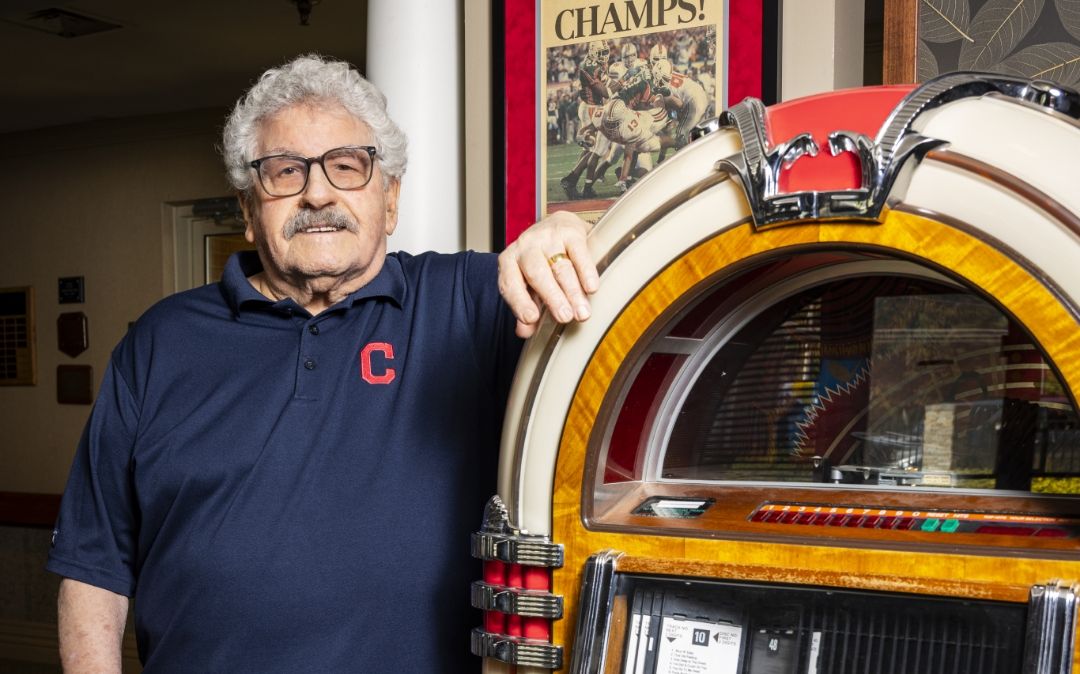 A resident shows his sports allegiance next to the campus jukebox at Willow Brook Home in Columbus, Ohio, capturing the personality of senior community life.
